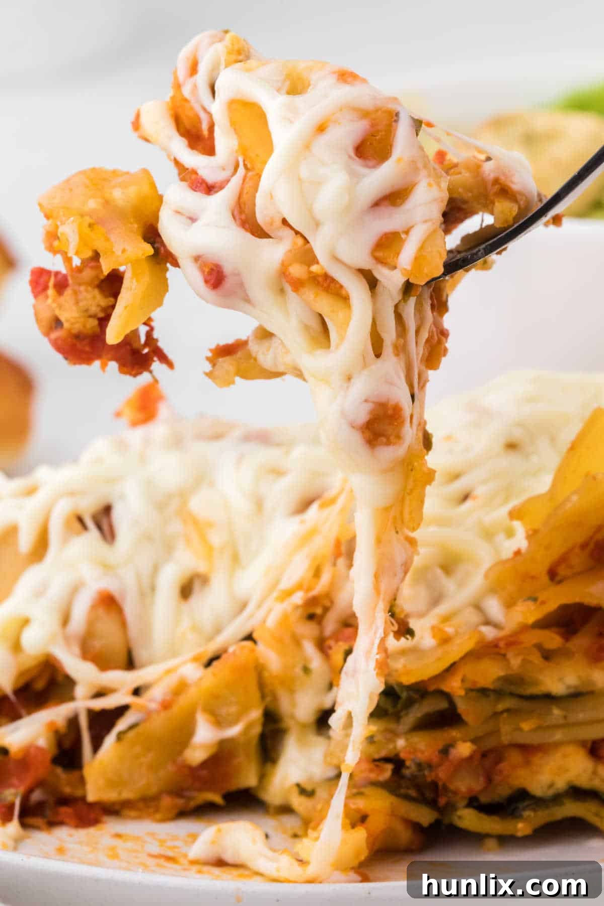 A fork lifting a piece of slow cooker lasagna, highlighting its melty cheese pull.