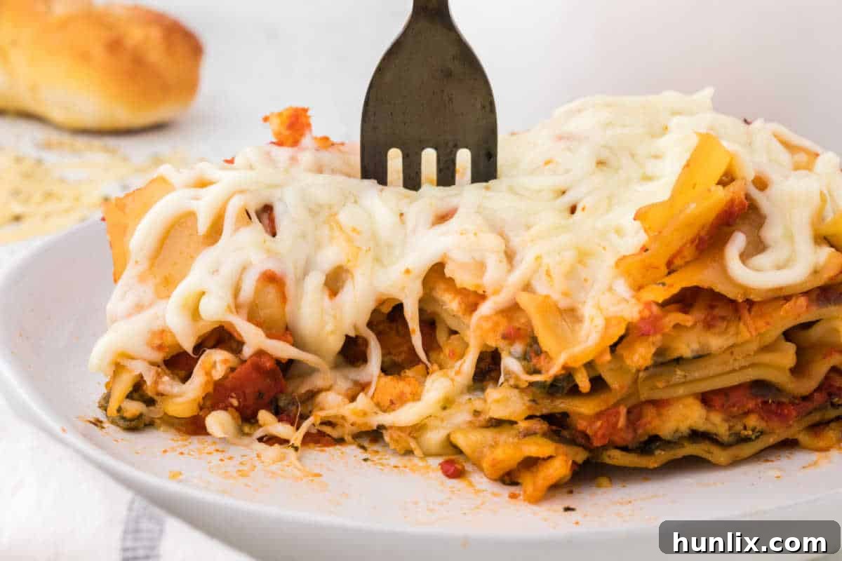 A fork lifting a piece of slow cooker lasagna from a plate, highlighting the delicious layers.
