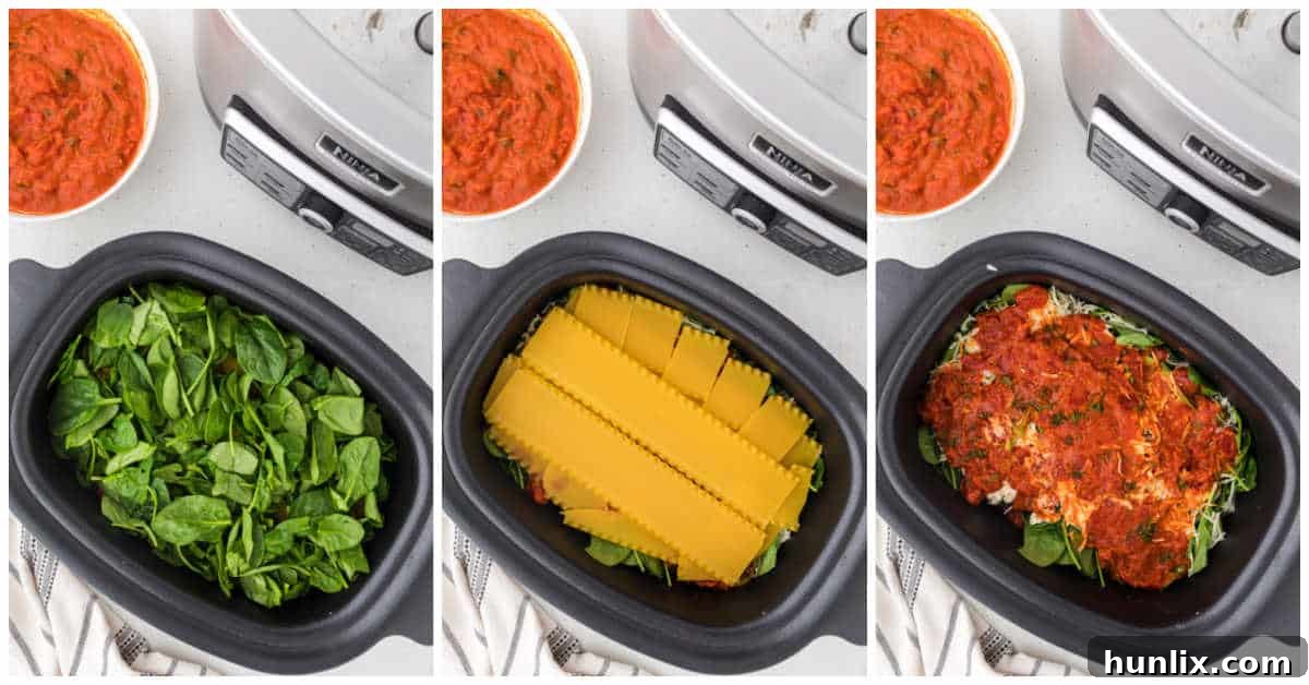 Layers of sauce, noodles, and spinach assembled in a slow cooker for lasagna.
