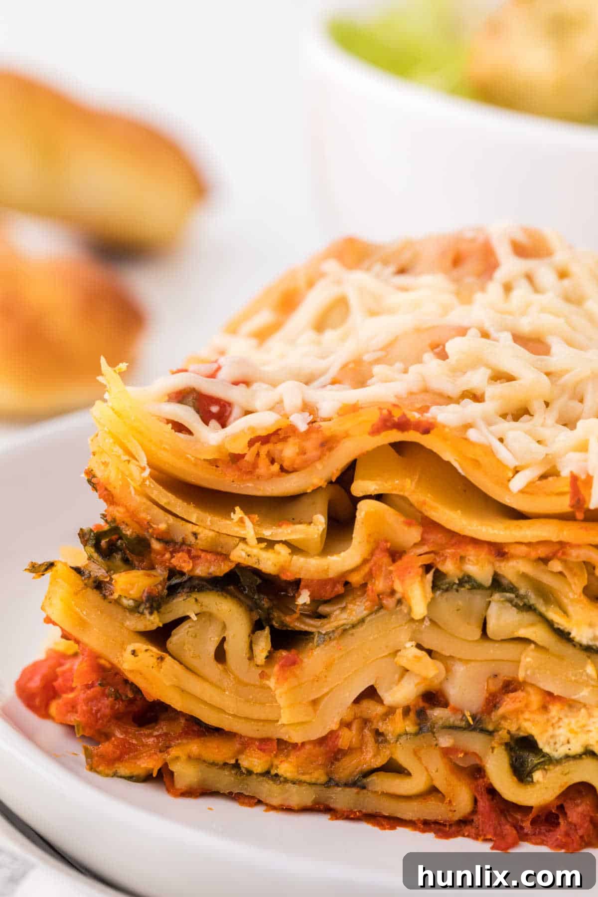 A slice of slow cooker lasagna on a plate, showing perfectly cooked layers of pasta, cheese, and sauce.