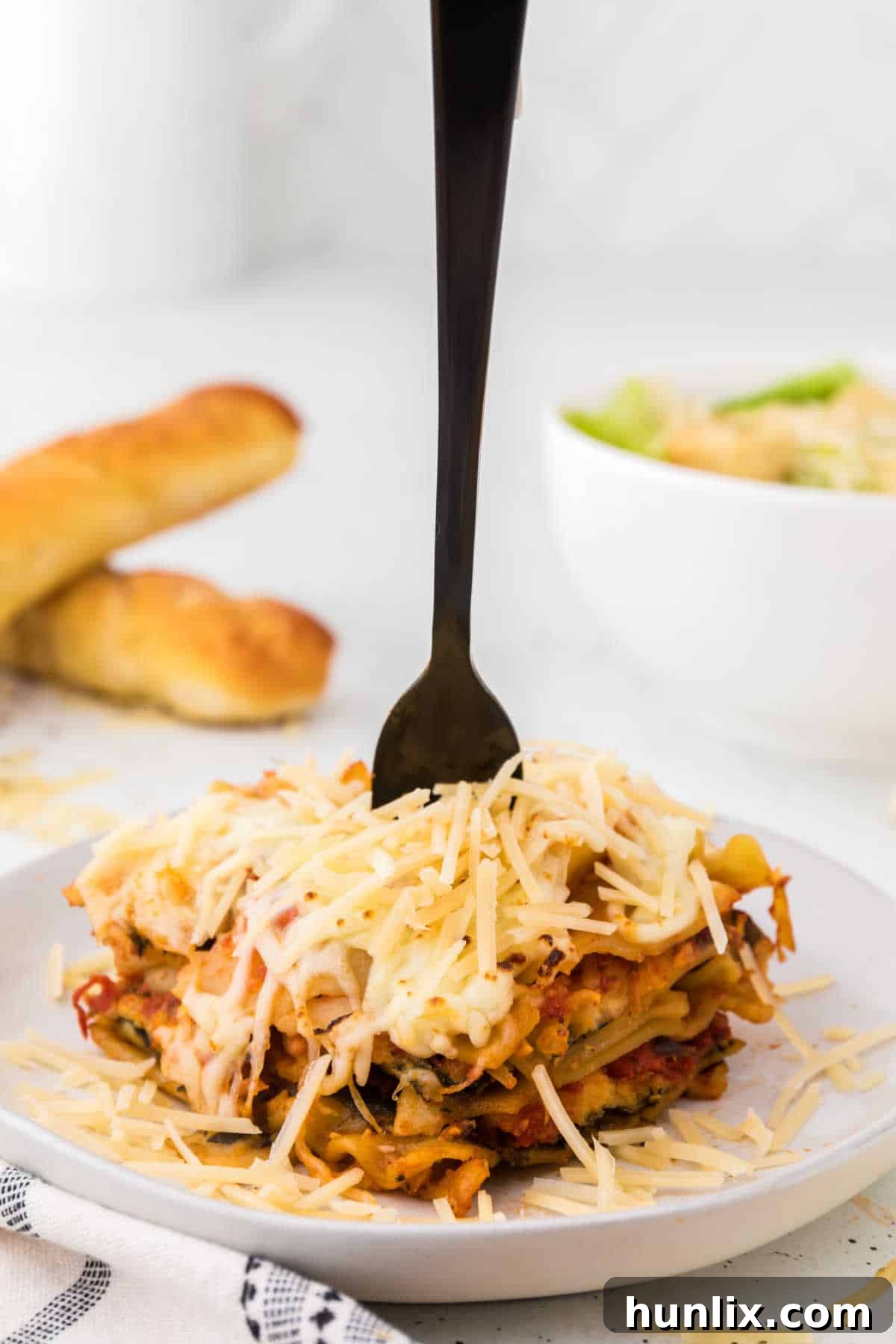 A piece of slow cooker lasagna on a plate with a fork, emphasizing its appetizing appearance.