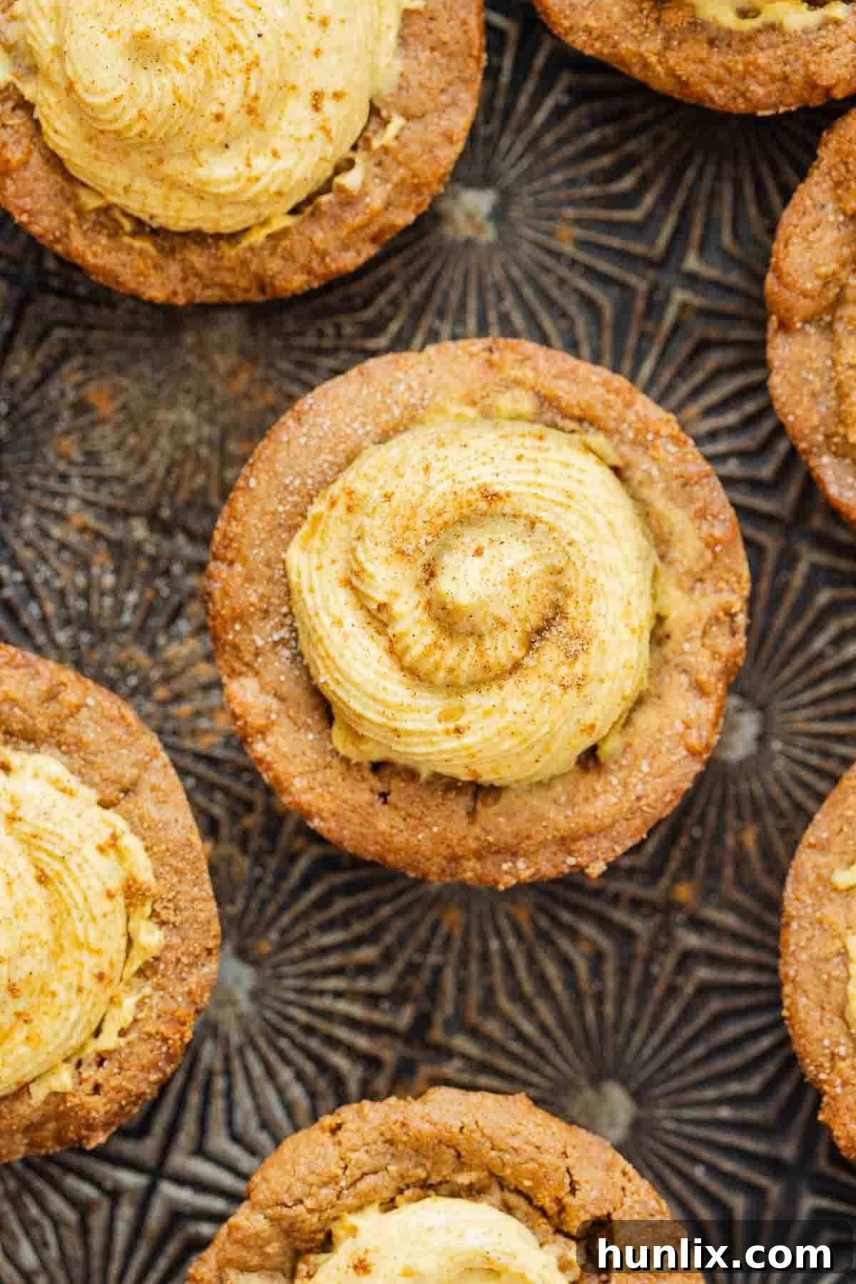 Autumn's Embrace Cakelets 7 Several finished pumpkin spice cake cups artfully arranged on a decorative wooden surface, highlighting their inviting appearance and perfect presentation.