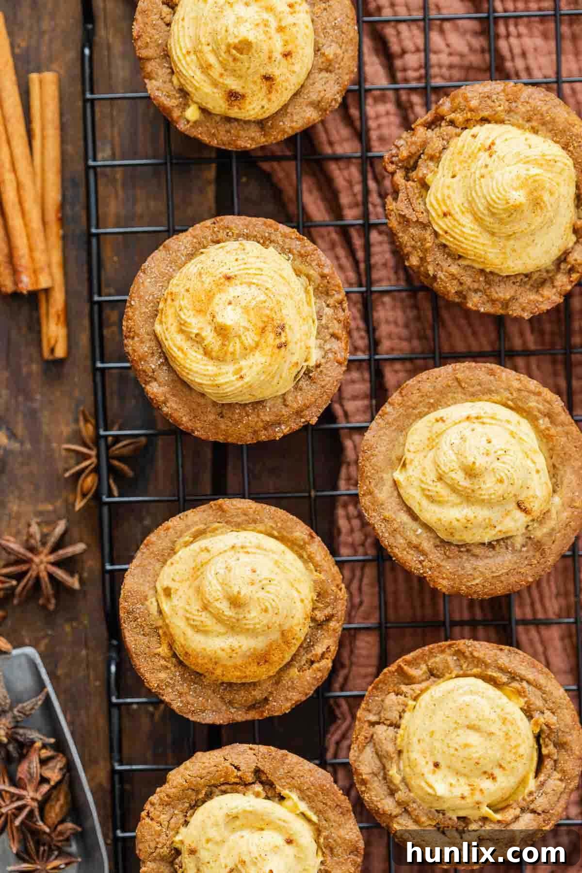 Autumn's Embrace Cakelets 8 Freshly baked pumpkin spice cake cups cooling on a wire rack, showcasing their perfect golden-brown color and inviting cup shape, almost ready for their creamy filling.