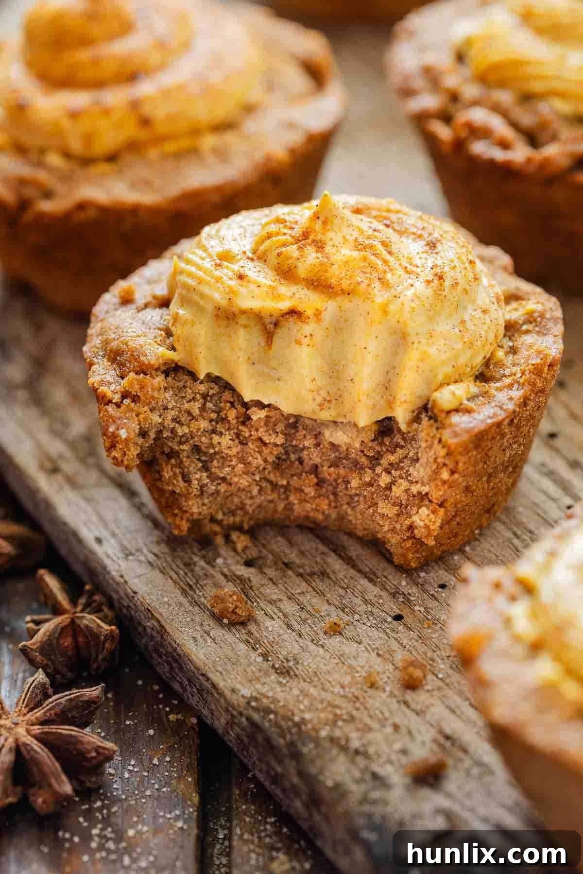 Autumn's Embrace Cakelets 9 A close-up shot of a pumpkin spice cake cup with a bite taken out, revealing the creamy cheesecake filling and moist cake layers, sitting on a rustic wooden surface.