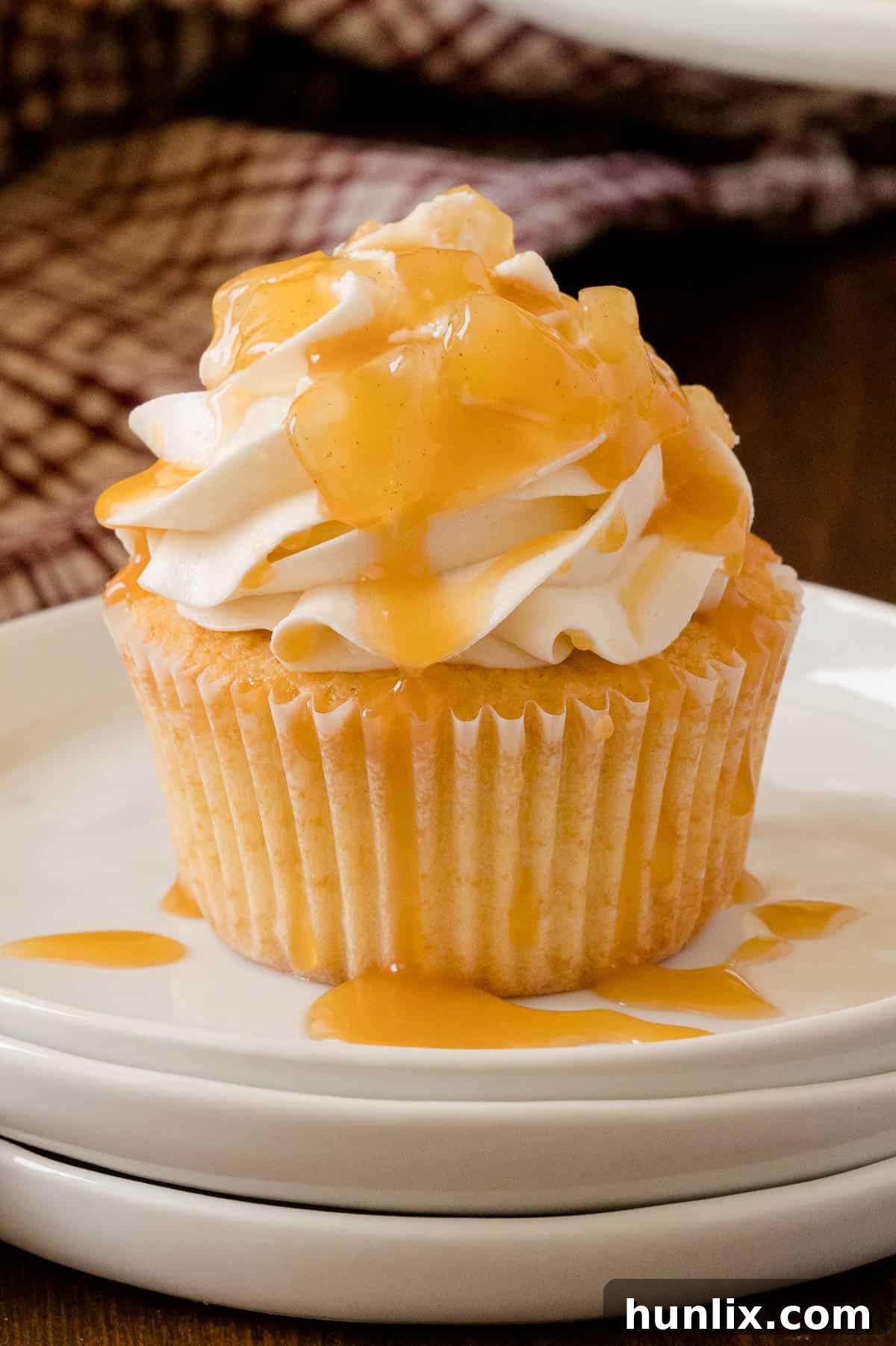 Decadent Caramel Apple Cupcakes 4 A trio of Caramel Apple Cupcakes on a rustic wooden surface, highlighting their homemade charm.