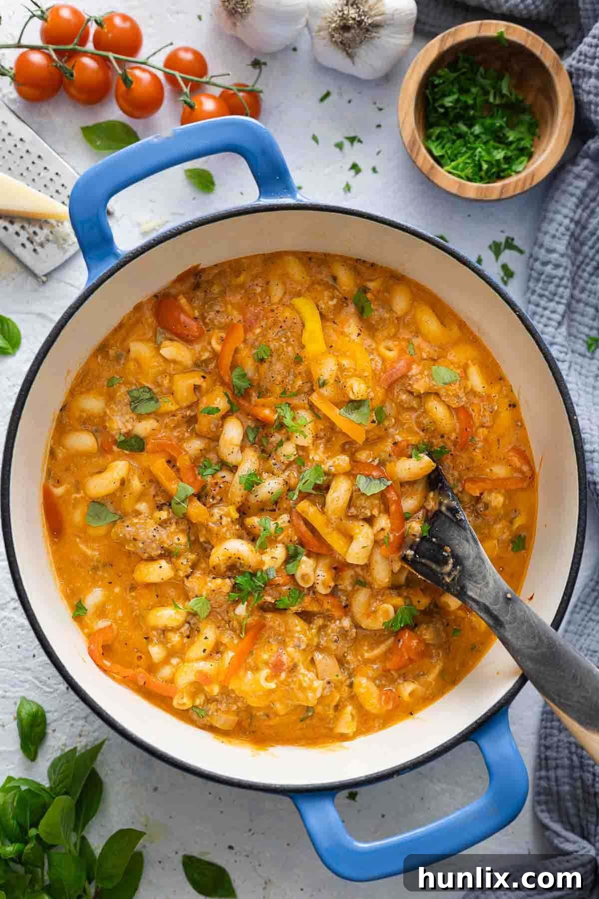 Spicy Sausage Skillet Pasta with Peppers 2 A large pot of vibrant spicy sausage and pepper one-pot pasta, ready to be served, with a spoon visible.