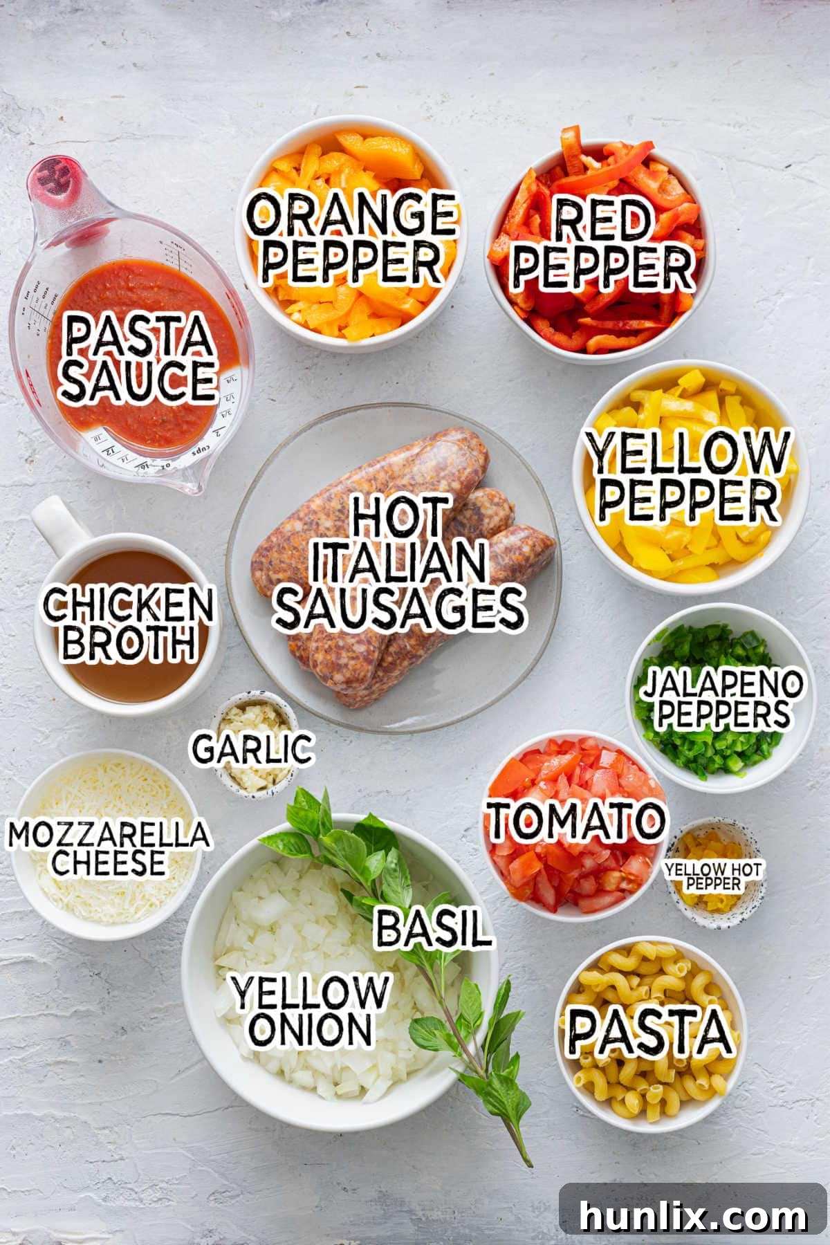 Spicy Sausage Skillet Pasta with Peppers 3 Assorted ingredients laid out on a cutting board, including bell peppers, jalapeños, onions, garlic, and Italian sausages.