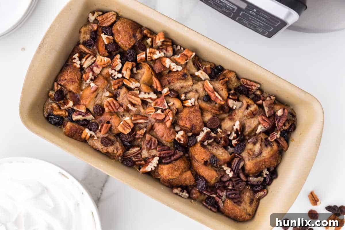 A slow cooker containing a baking dish filled with cinnamon raisin bread pudding, perfectly cooked and ready to be served.