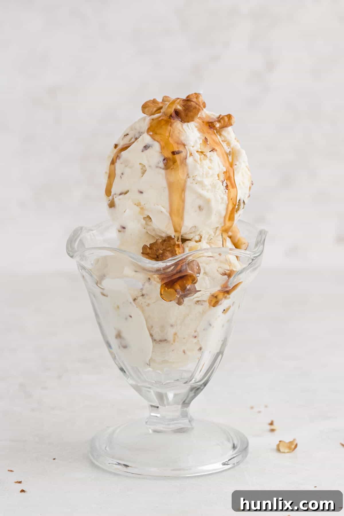 Maple walnut ice cream in a parfait dish with maple syrup on top.