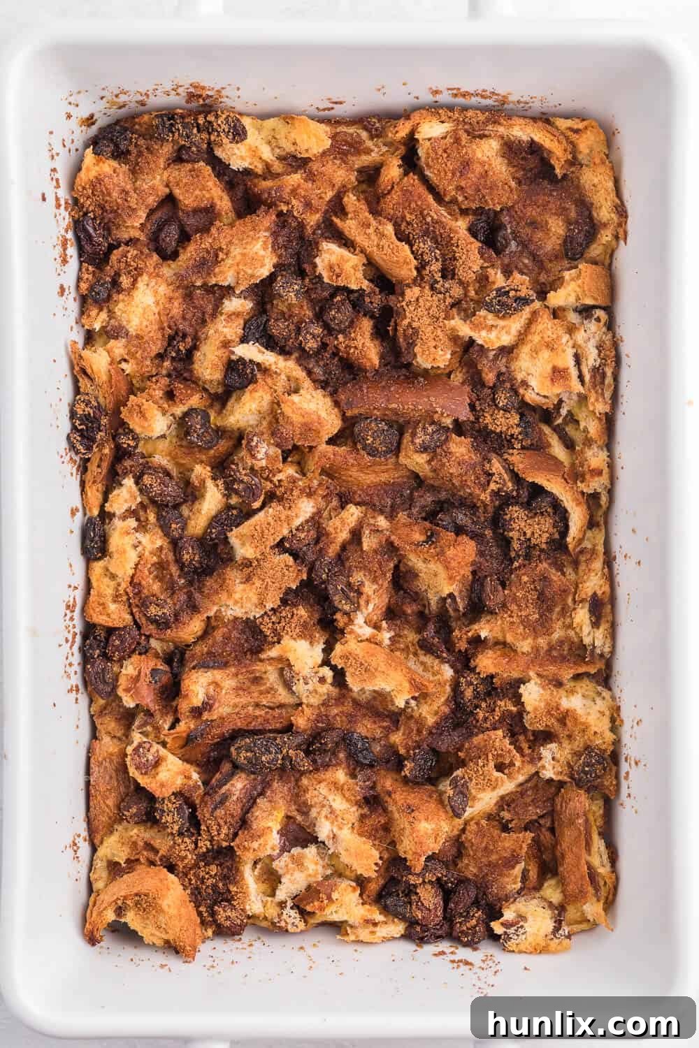 A beautifully baked Cinnamon Raisin French Toast Casserole in a white baking dish, ready to be served.