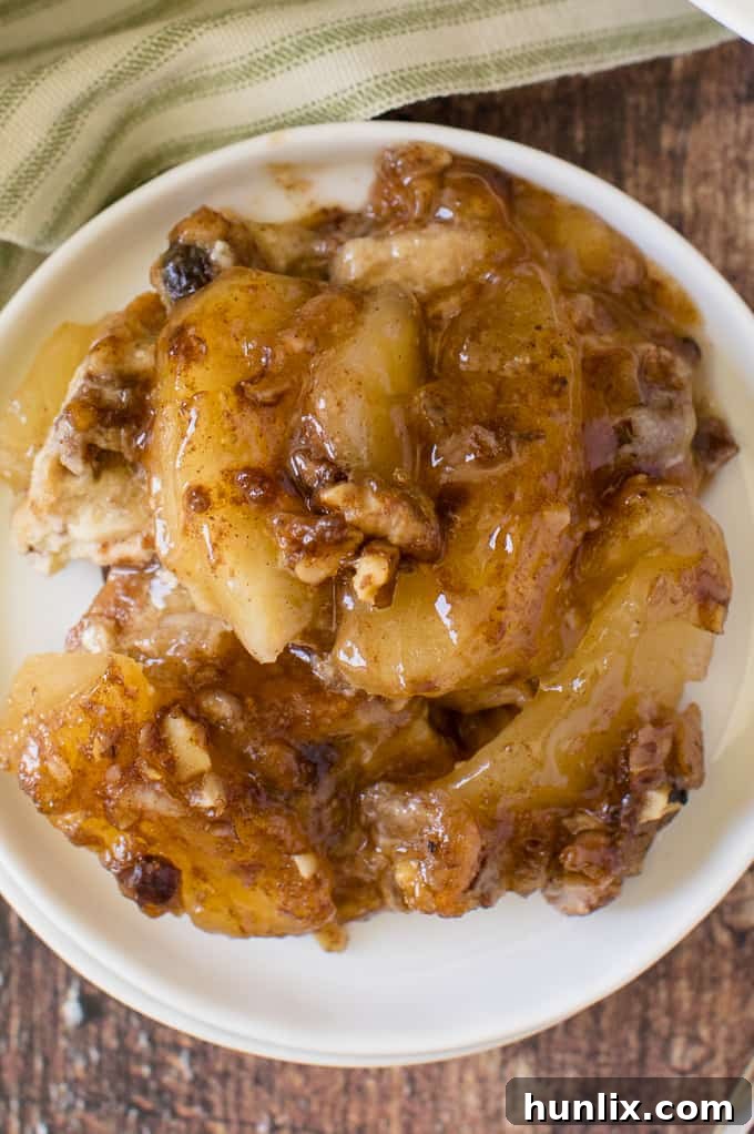 A close-up of a slice of Apple Pie French Toast Casserole on a white plate, showing the apple pieces and custardy bread.