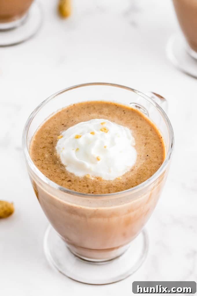 Slow Cooker Peanut Butter Hot Cocoa Bliss 7 A single mug of slow cooker peanut butter hot chocolate, topped with whipped cream and a mini peanut butter cup, with chocolate drizzle.