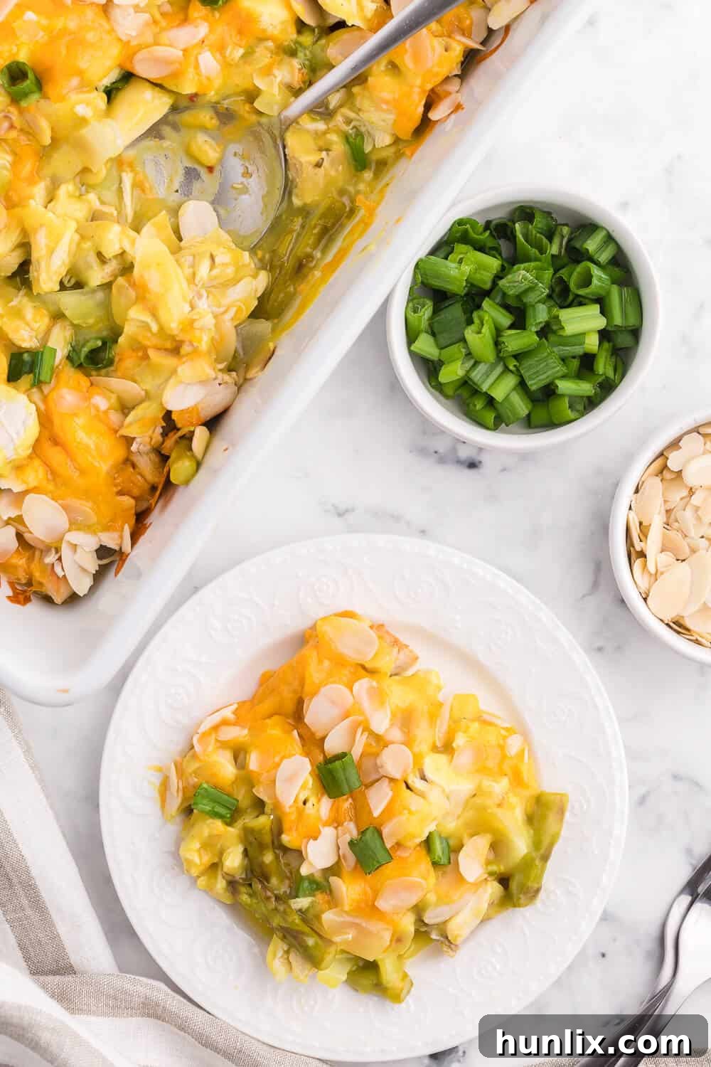 A serving of Chicken Asparagus Bake in a bowl, showing the creamy sauce, chicken, asparagus, and melted cheese, garnished with fresh green onions.