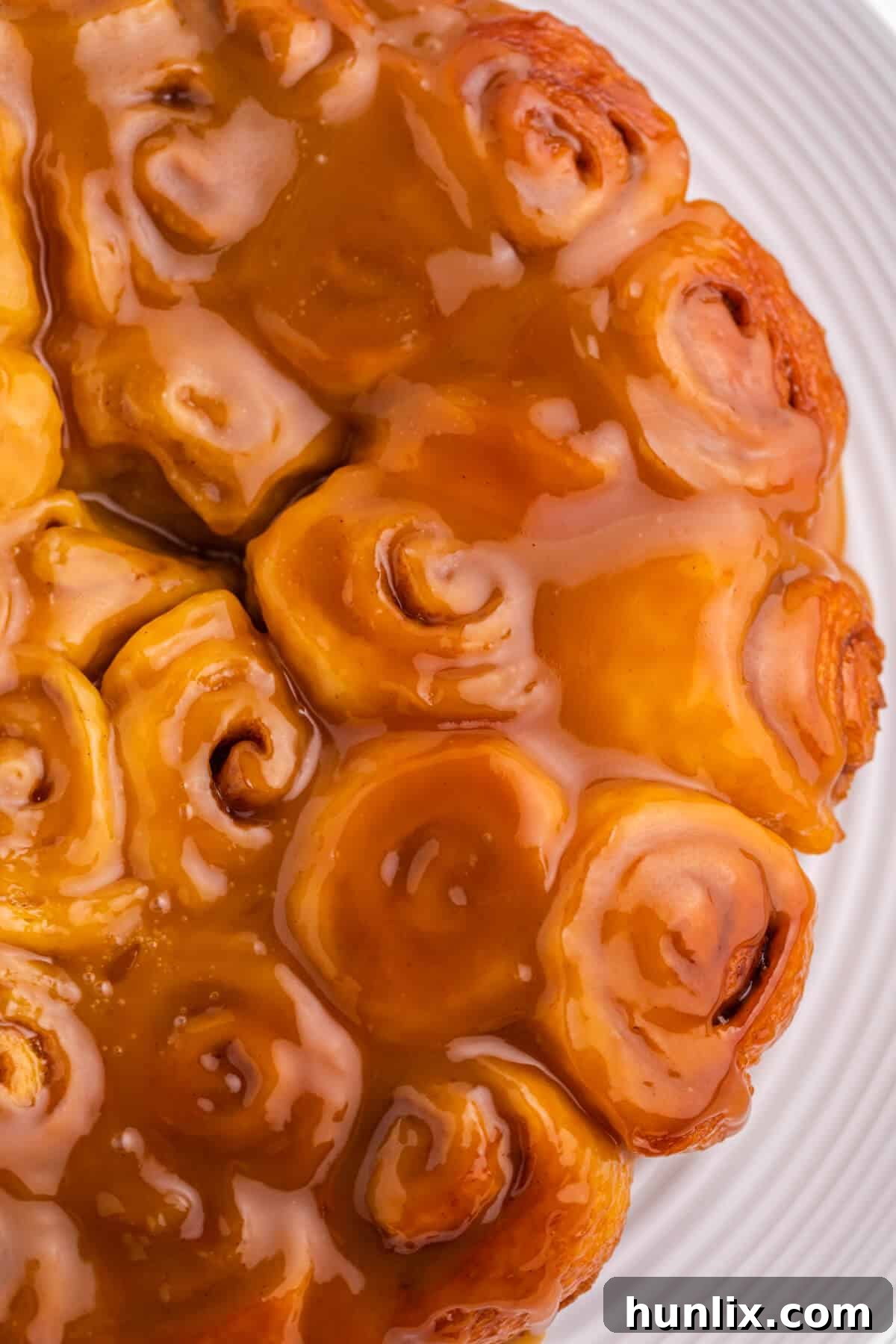 Rum-Kissed Mini Cinnamon Swirls 3 A close-up shot of Mini Rum Butter Cinnamon Rolls, showing their sticky, glossy coating of rum butter sauce on a white plate.