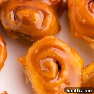 Rum-Kissed Mini Cinnamon Swirls 7 Mini rum butter cinnamon rolls on a plate, gleaming with rum butter sauce.