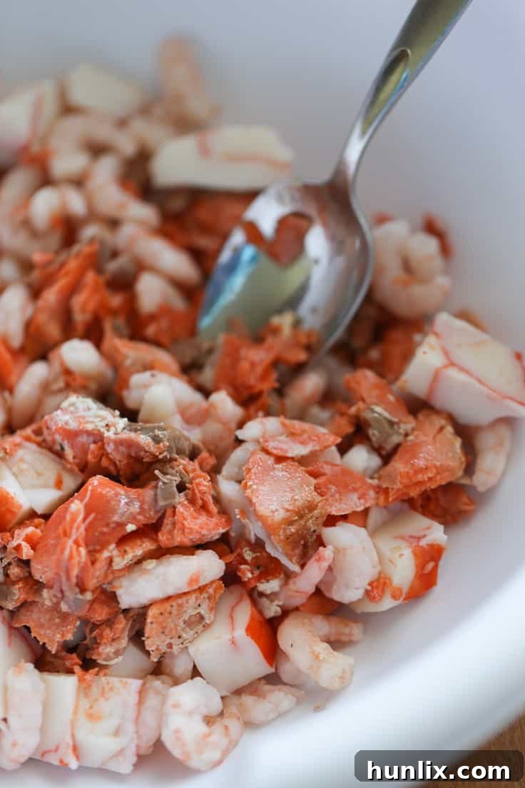 Mixed seafood (salmon, shrimp, crab) in a bowl, ready for the Caesar salad.