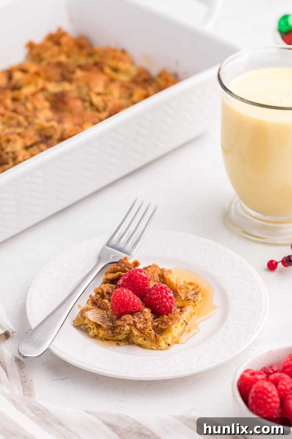 A slice of eggnog breakfast casserole on a white plate, showing a rich, creamy texture.