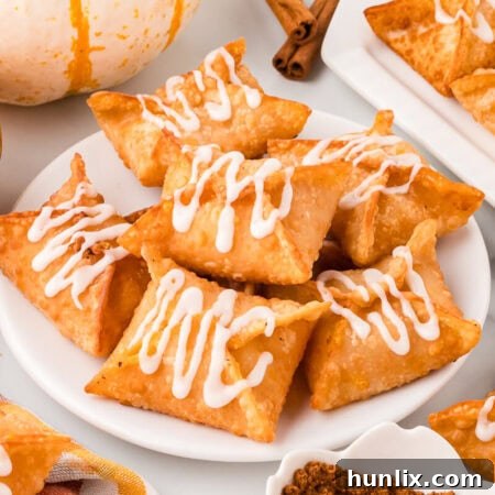 A pumpkin cream cheese wonton on a plate with maple glaze drizzled over it.