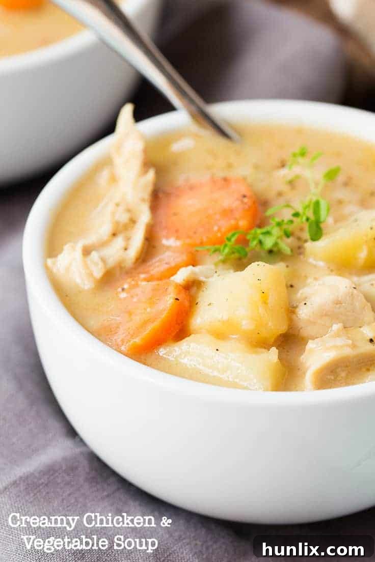A bowl of creamy chicken and vegetable soup on a rustic table, highlighting its comforting appeal.