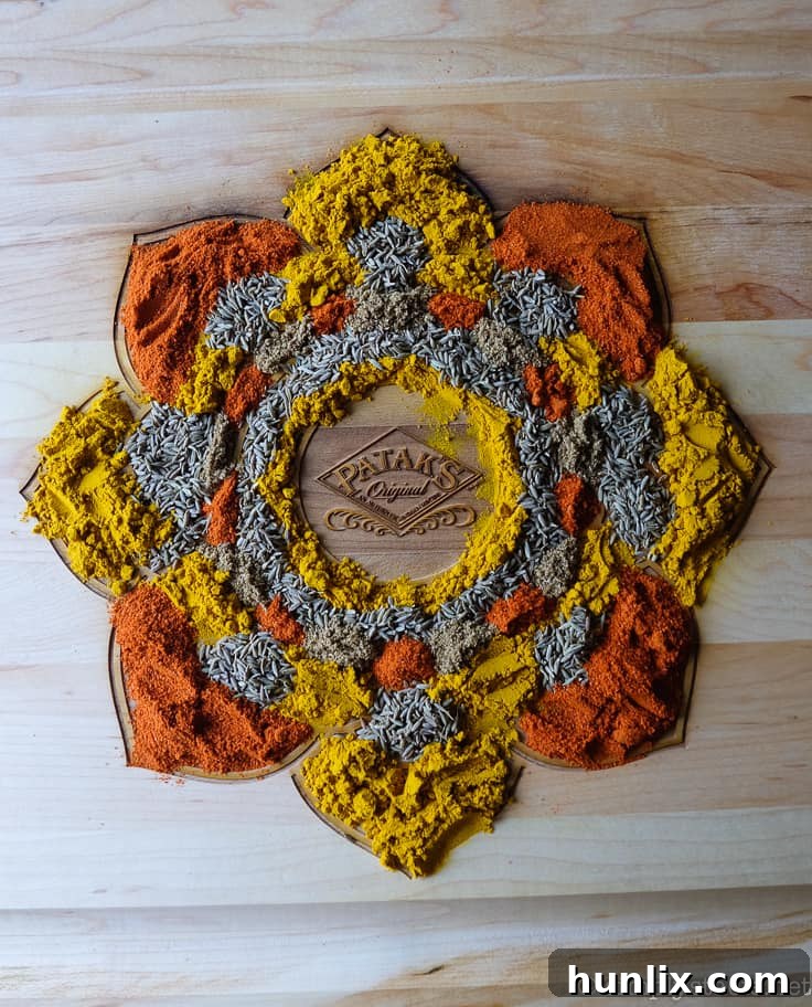 Hands carefully arranging various spices to form a vibrant Rangoli design on a wooden board.