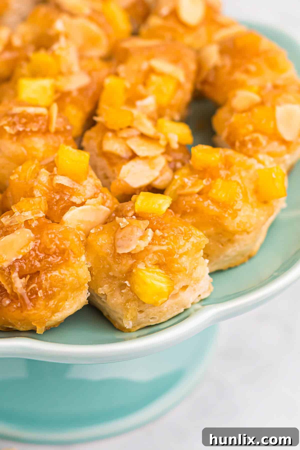 Pineapple Paradise Sticky Buns with Coconut Caramel Sauce 8 A stack of delicious pineapple sticky buns with coconut caramel on a white platter, ready for sharing or serving, highlighting their gooey texture and tropical appeal.