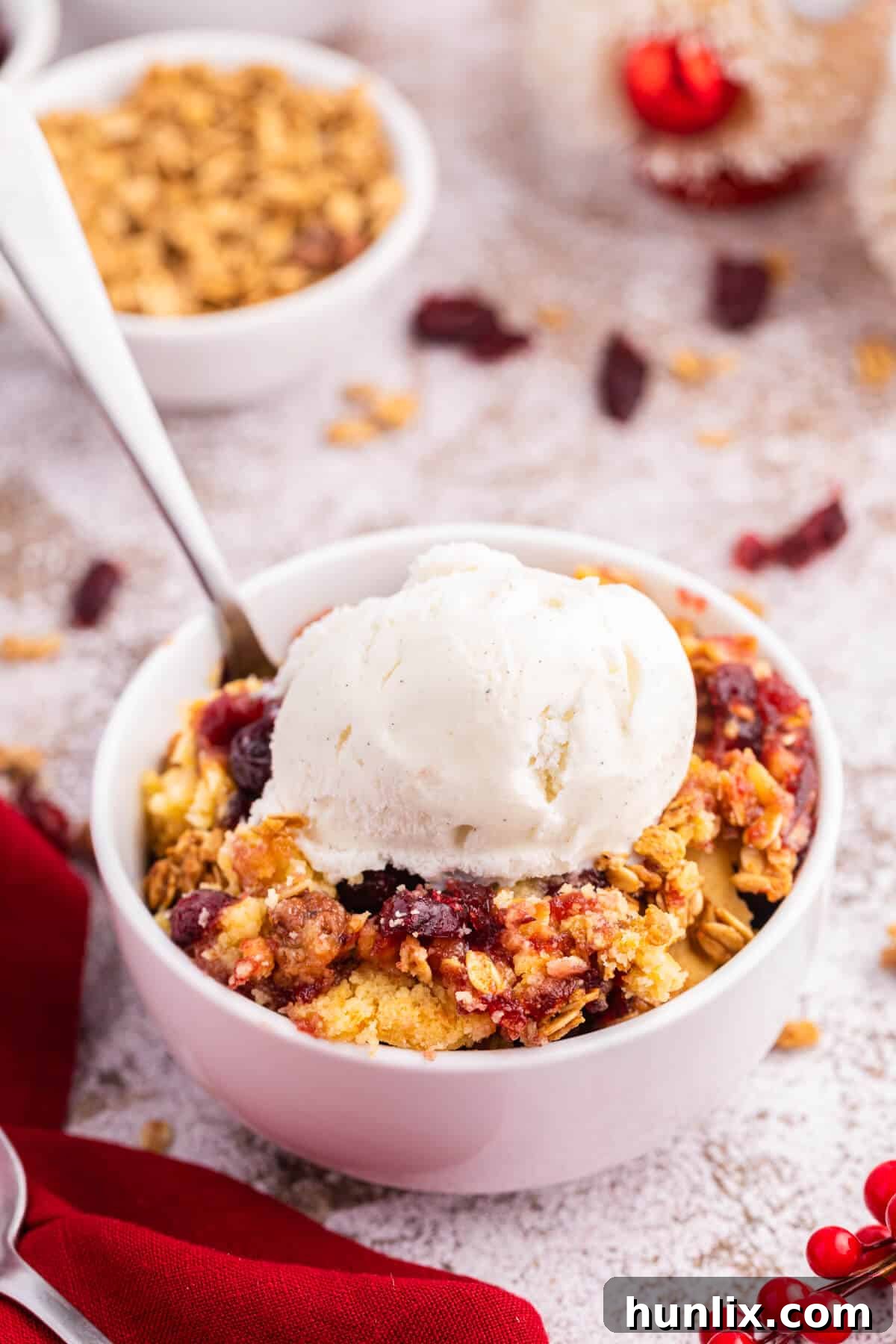 Cranberry cobbler dump cake with vanilla ice cream on top in a bowl.