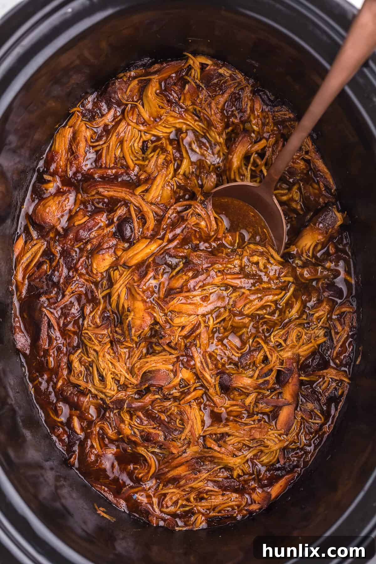 Close-up of Slow Cooker Cranberry Chicken, showing the rich, dark red sauce and tender chicken pieces, ready to be shredded.
