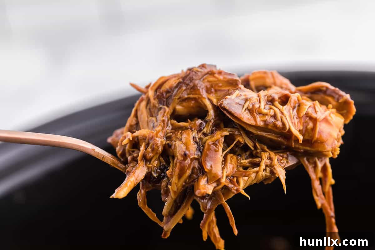 Plated Slow Cooker Cranberry Chicken, shredded and served with fresh thyme, highlighting its rich sauce and tender texture.