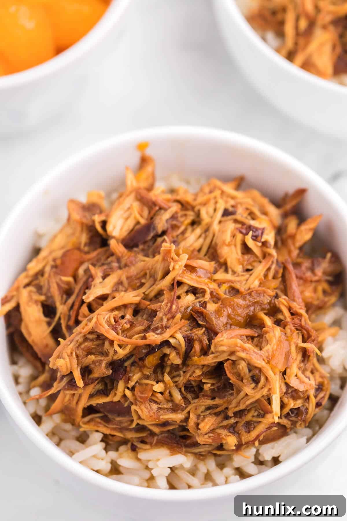 Close-up of shredded Slow Cooker Cranberry Orange Chicken with mandarin orange slices and green onions, ready to be served.