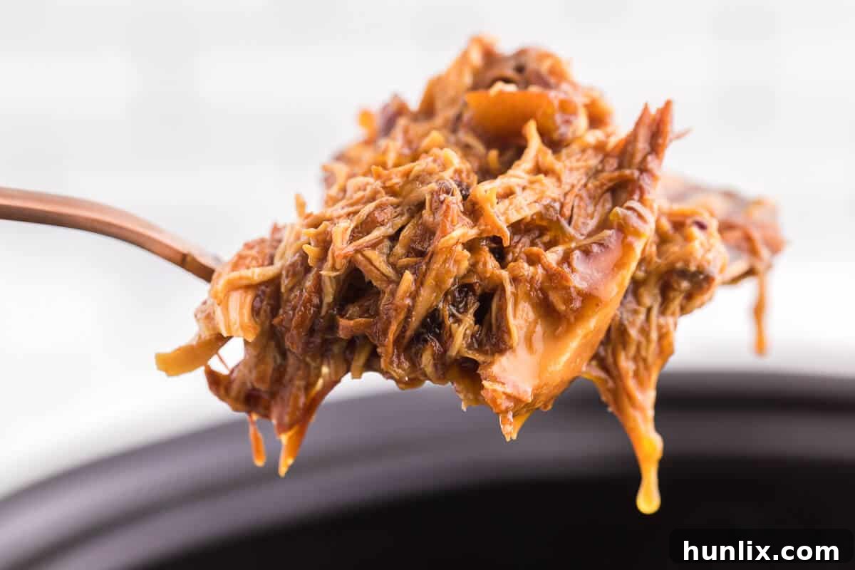 A serving of Slow Cooker Cranberry Orange Chicken over white rice with fresh cilantro garnish, showcasing its delicious texture and vibrant sauce.