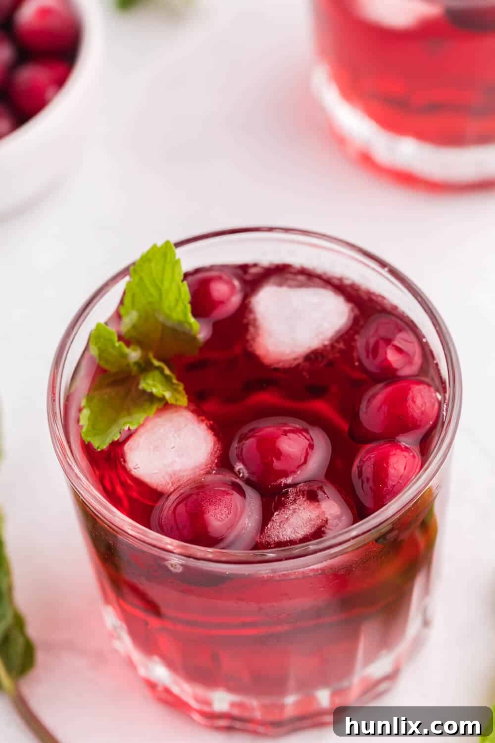 The finished cranberry mint mocktail recipe on a white surface, ready to be served.