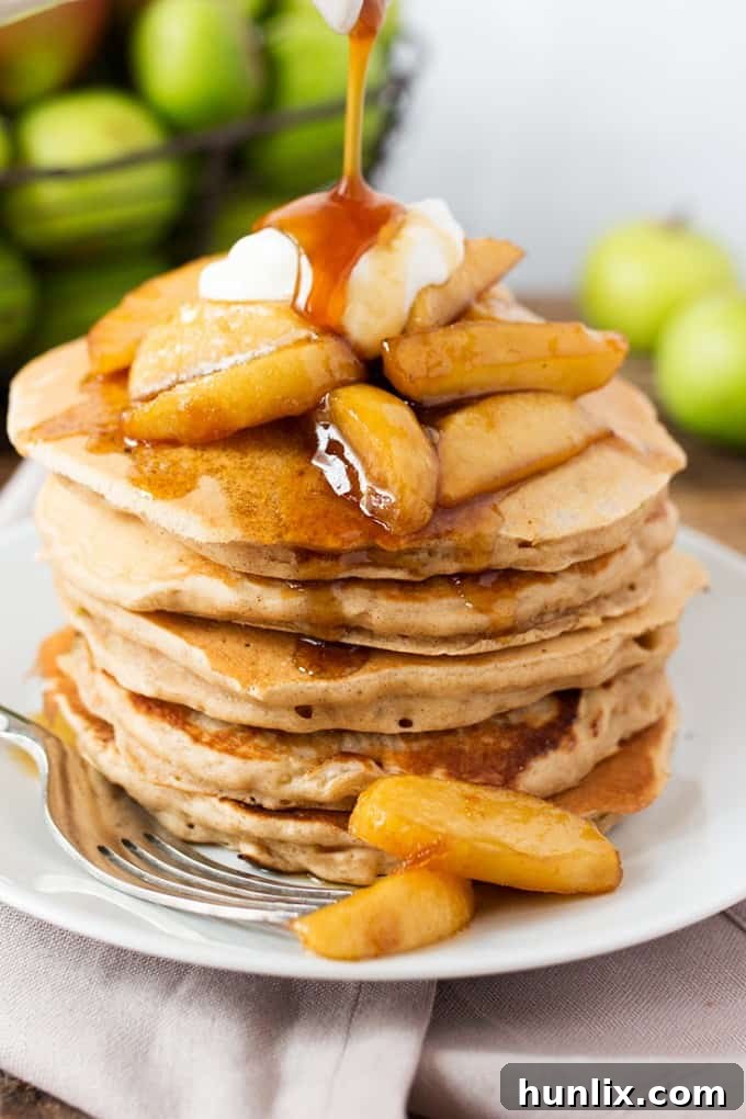 Tall stack of Apple Pie Pancakes, drizzled with syrup and topped with crème fraîche.