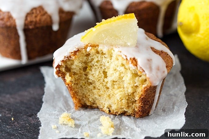 Zesty Lemon Drizzle Muffins with a sweet lemon glaze and candied lemon slices, perfect for a bright treat.