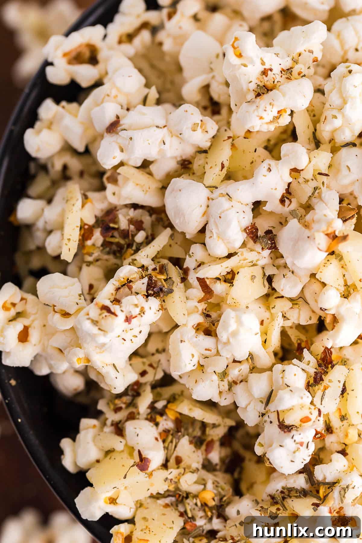 A detailed close-up shot of Pizza Popcorn, highlighting the crispy kernels beautifully coated with grated Parmesan, Italian seasoning, and red pepper flakes.