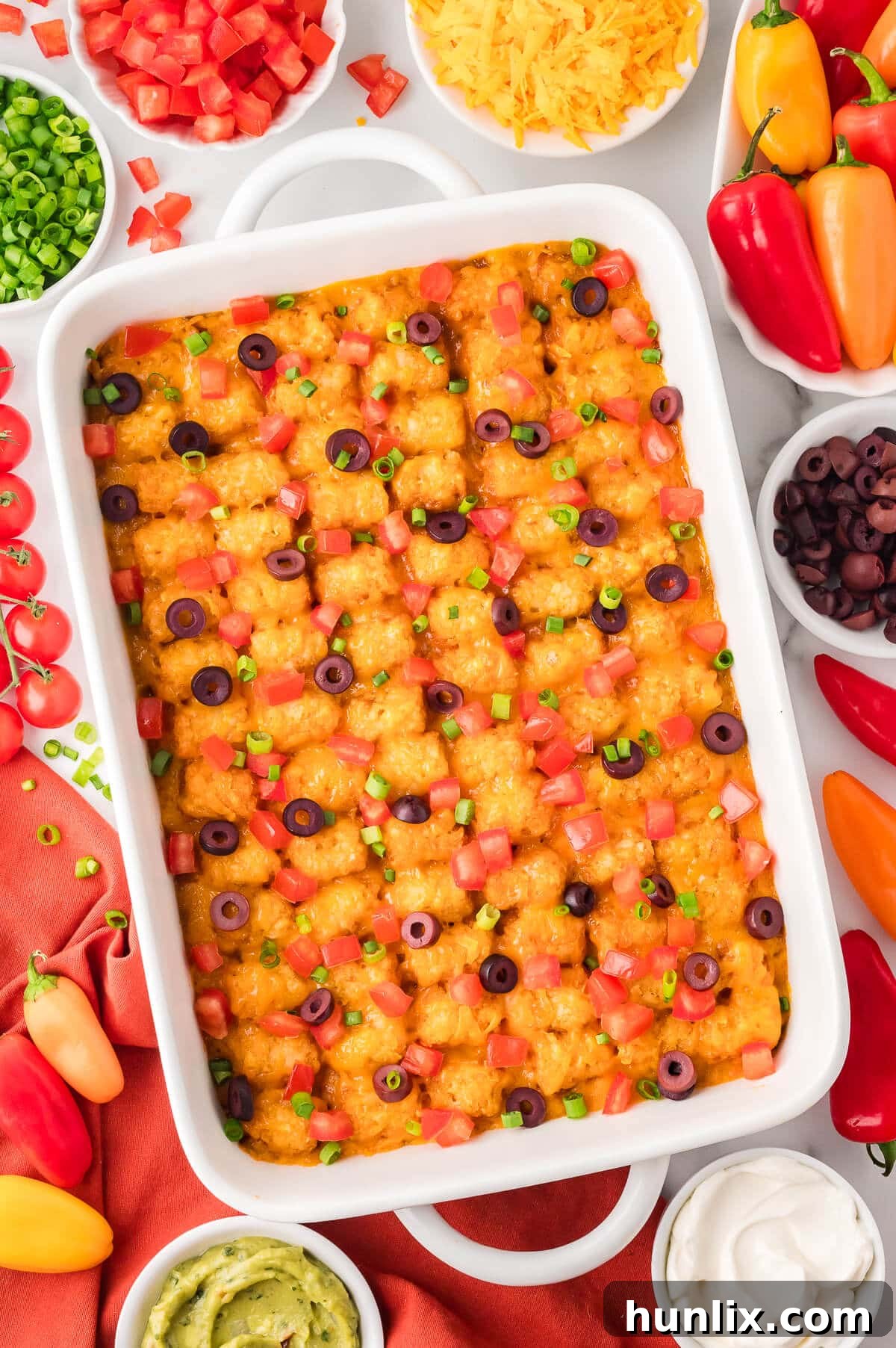 A pan of Mexican Tater Tot Casserole surrounded by ingredients.