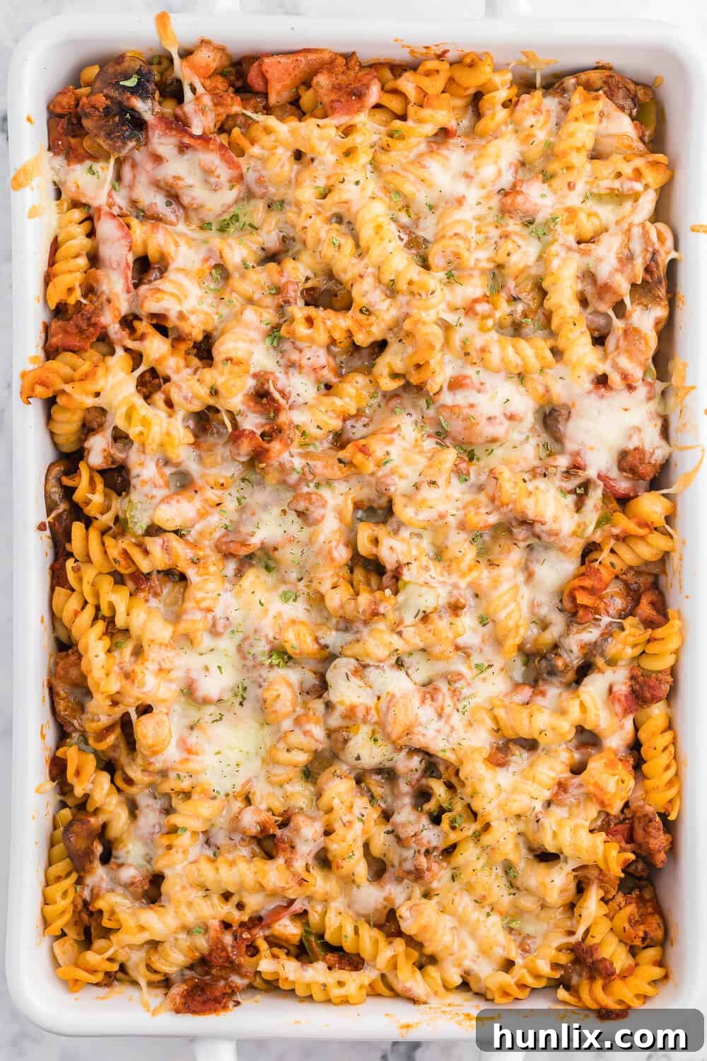 Meatzza Casserole - This crowd pleasing casserole recipe is packed with four kinds of meat, pizza sauce, veggies and oohey gooey cheese!