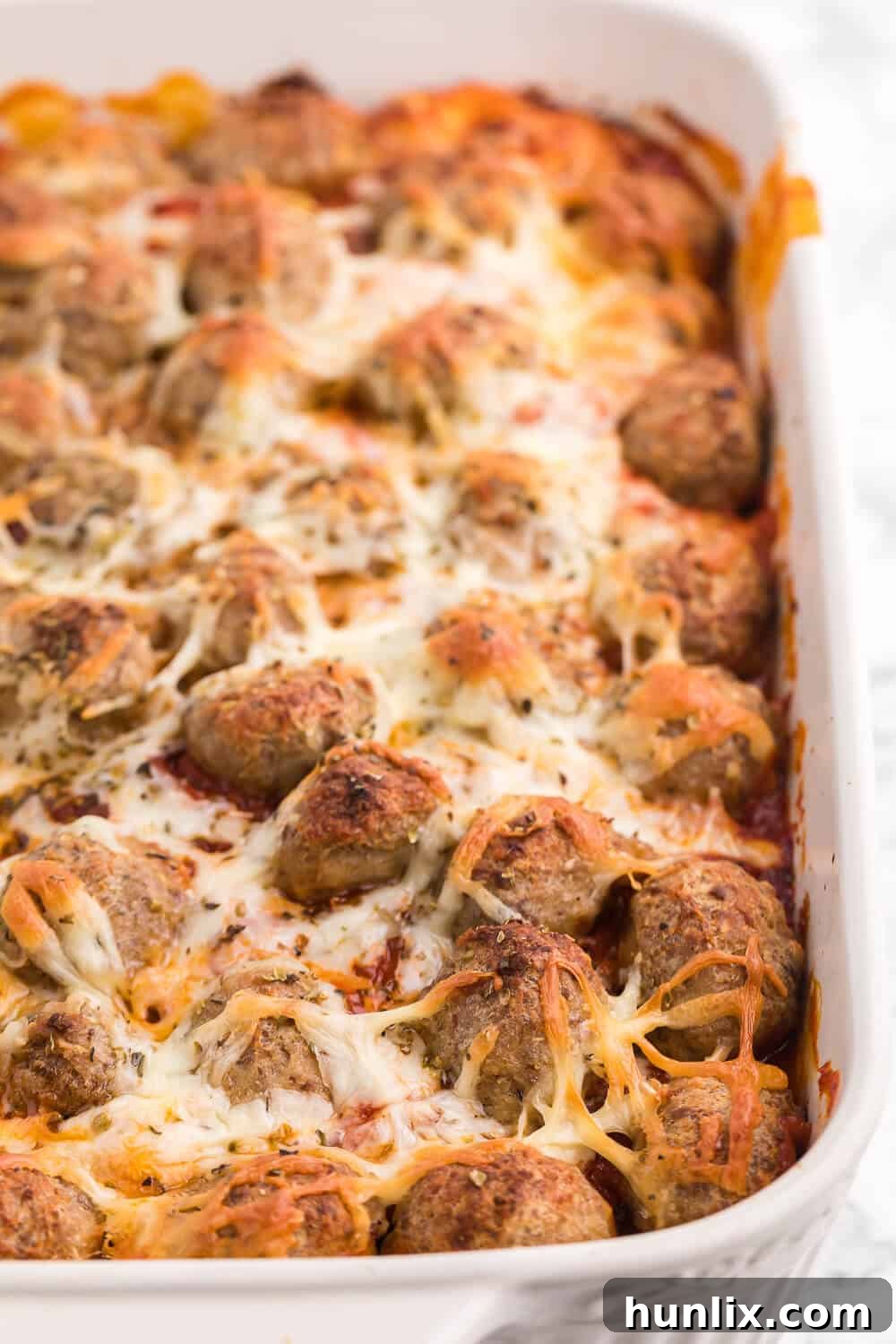 Close-up of bubbling Meatball Sub Casserole fresh from the oven, showing cheesy meatballs and biscuit base