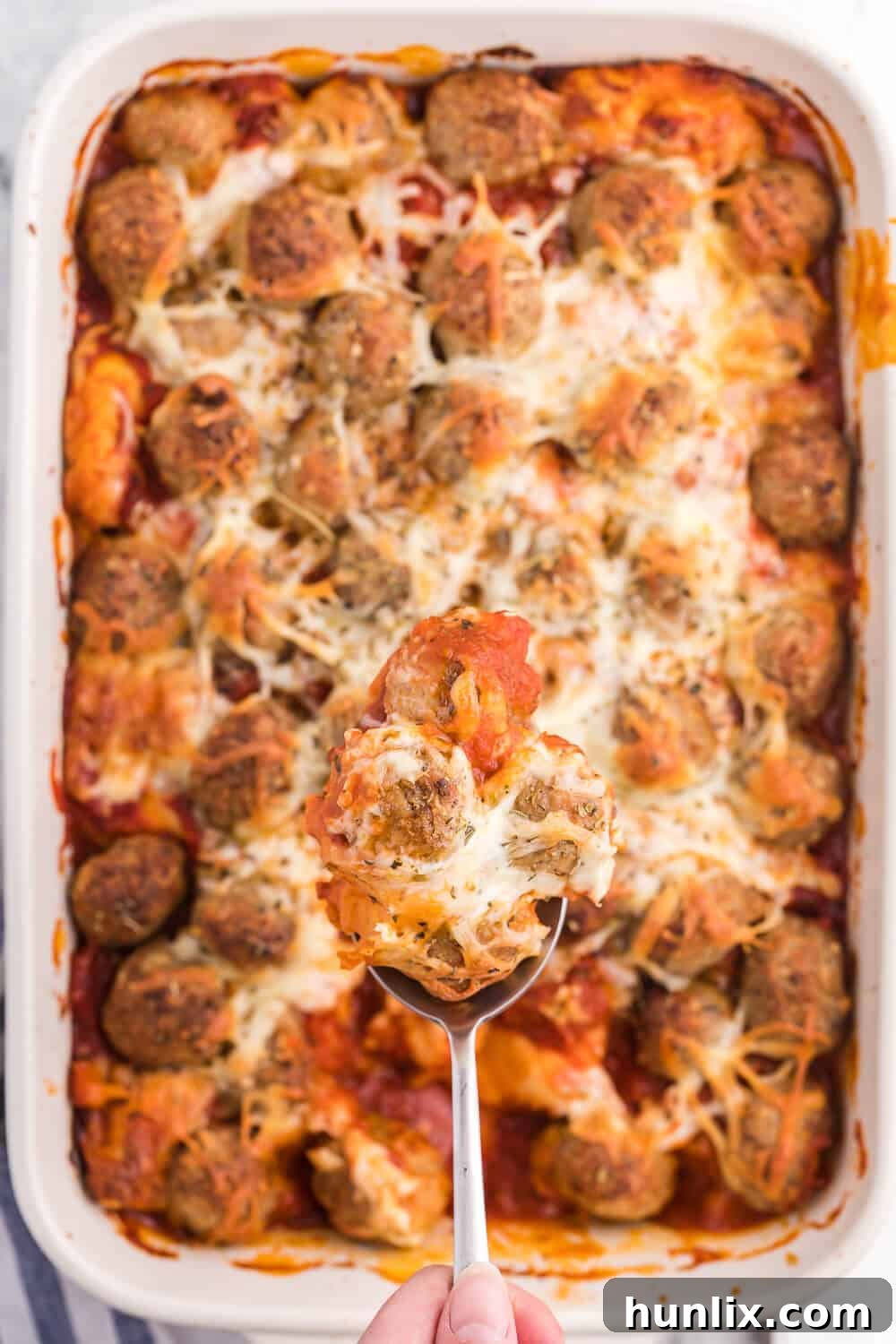 Layered Meatball Sub Casserole before baking, showing biscuits, sauce, meatballs, and cheese