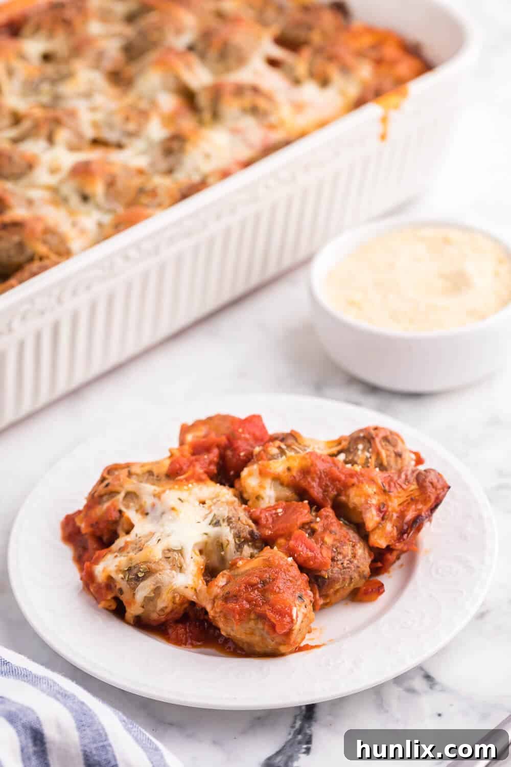 A serving spoon lifting a portion of Meatball Sub Casserole, showing the melty cheese