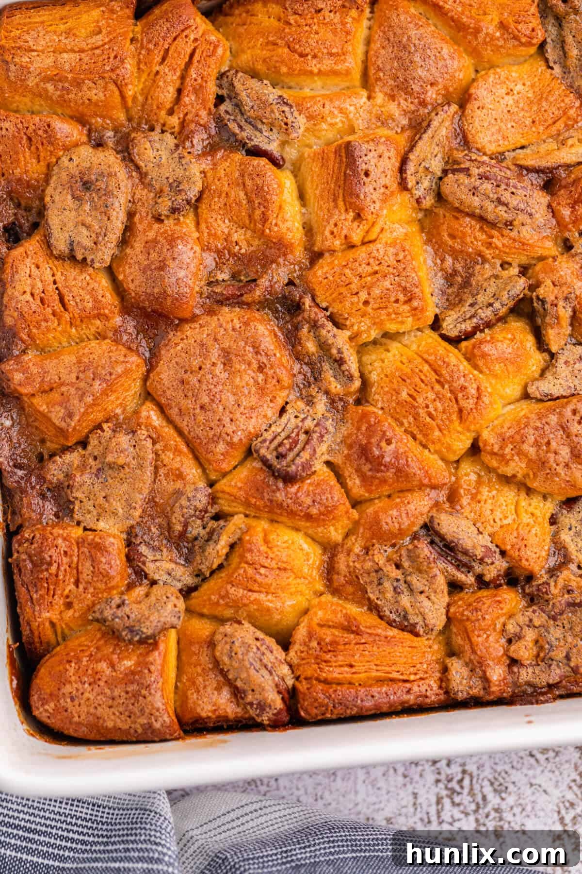 Pecan butter tart buns arranged neatly in a baking dish, golden brown and glistening with syrup.