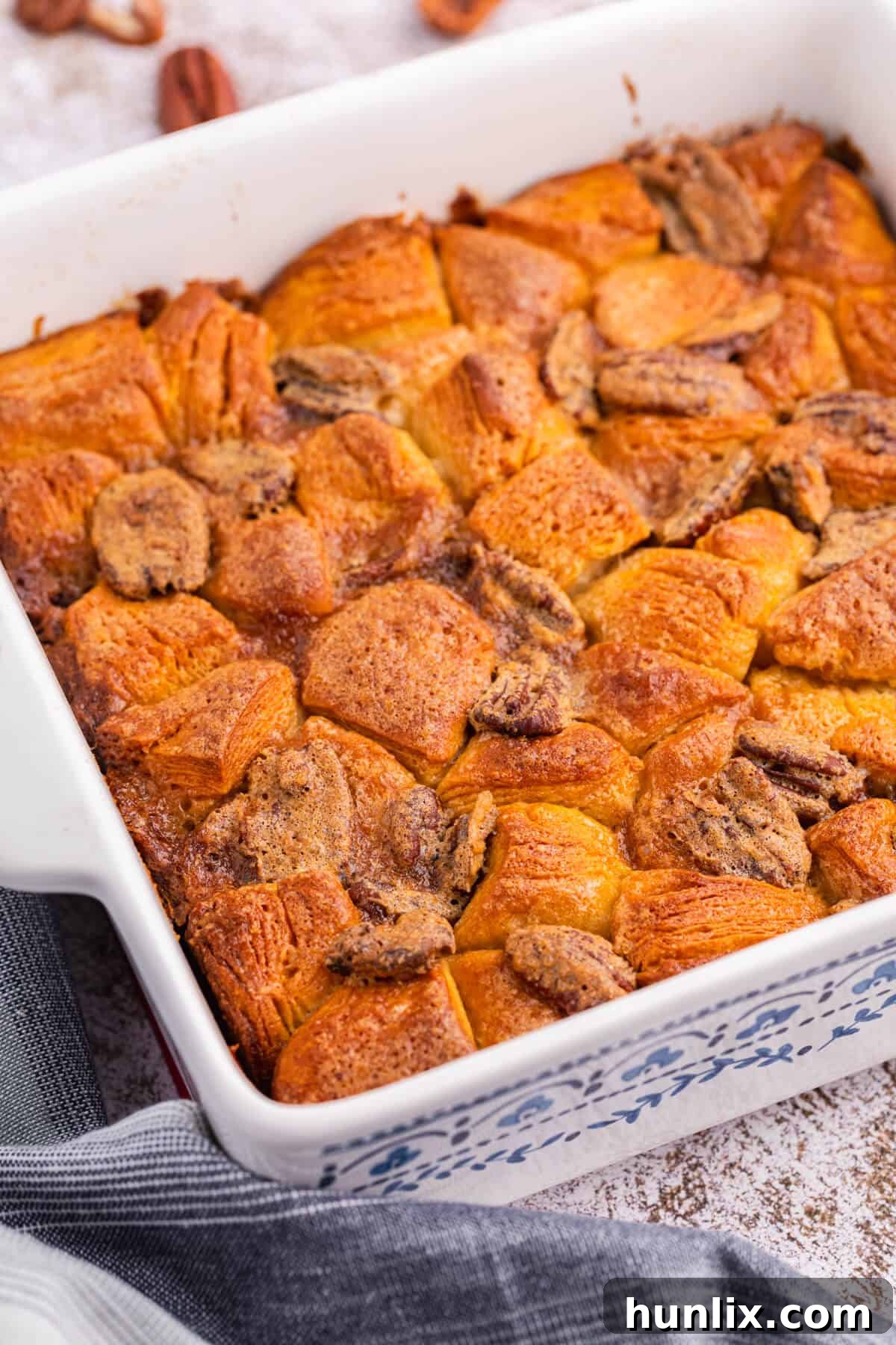 Close-up of baked Pecan butter tart buns in a square casserole dish, showing their golden tops and sticky filling.
