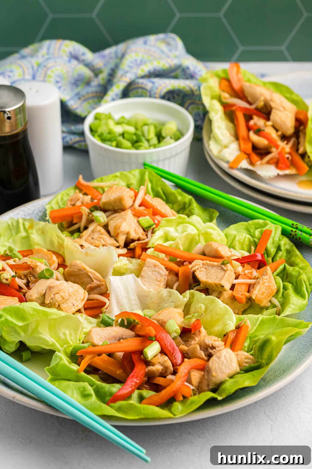 Freshly prepared Asian chicken lettuce wraps on a white plate, showcasing the vibrant filling and crisp lettuce.