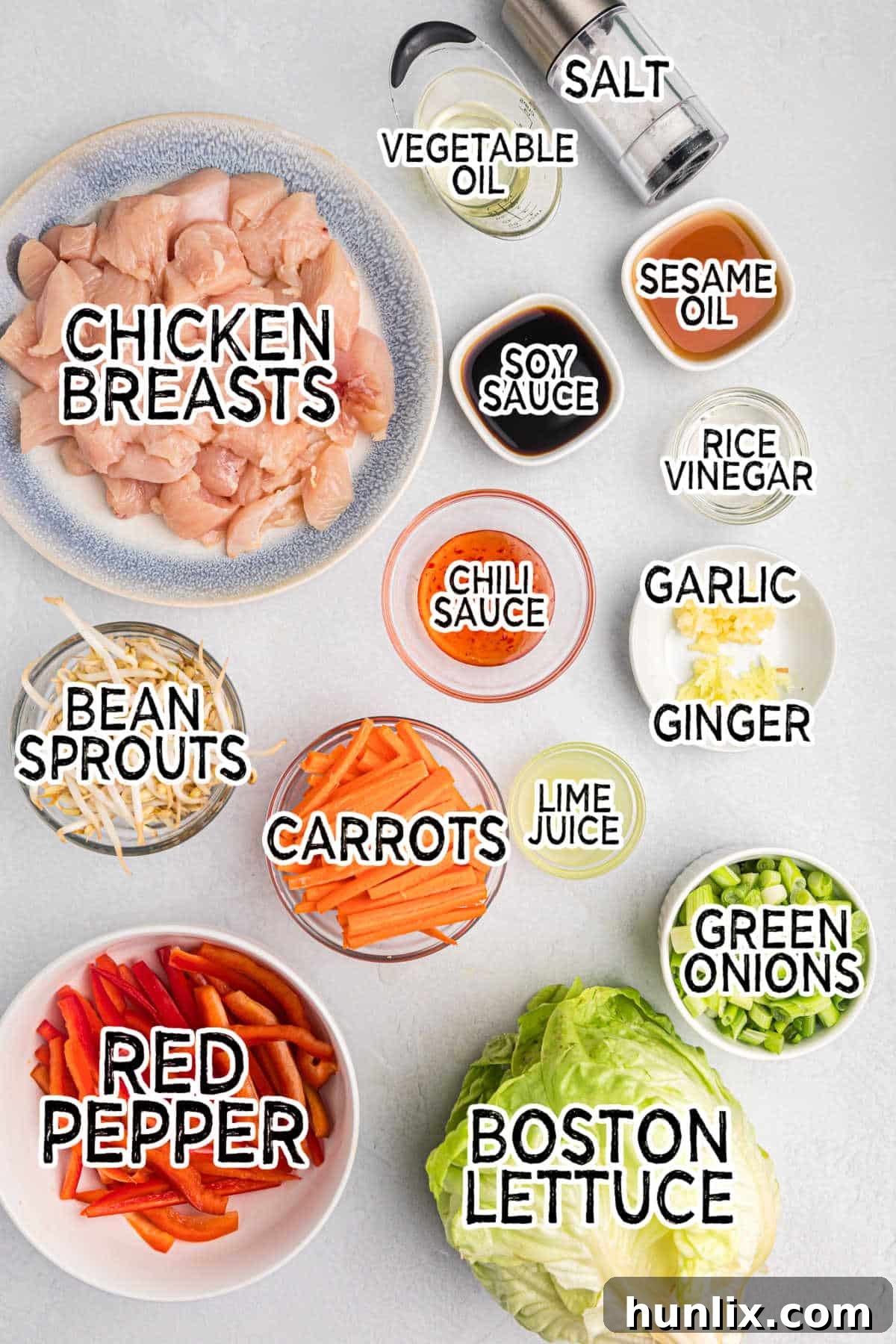 An array of fresh ingredients for Asian Chicken Lettuce Wraps laid out on a wooden board.