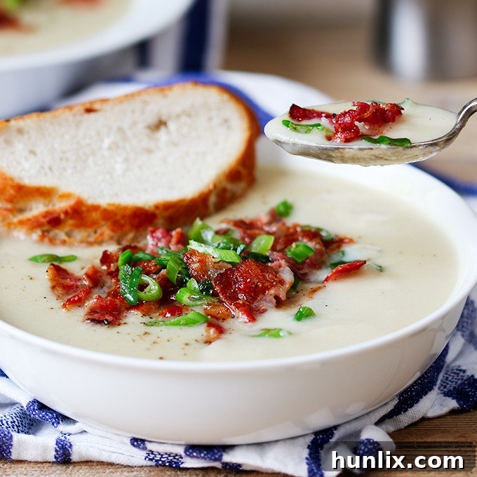 Creamy Cauliflower Bacon Bisque 4 A spoon laden with creamy cauliflower soup, adorned with crispy bacon bits and fresh scallions, ready to be enjoyed.