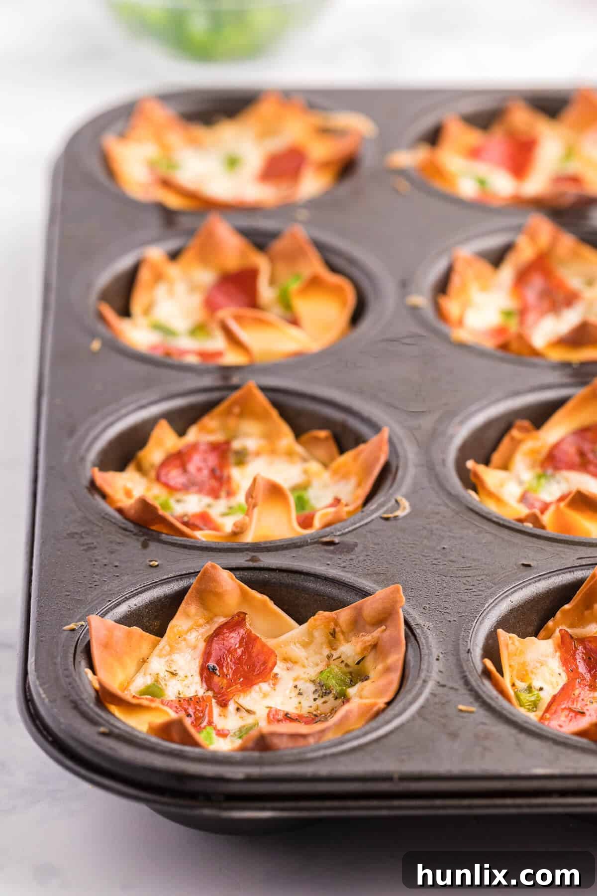 Pizza Wonton Cups Recipe - East meets West in this simple crunchy appetizer. A crispy wonton is filled with cheesy pizza goodness with any toppings you want!