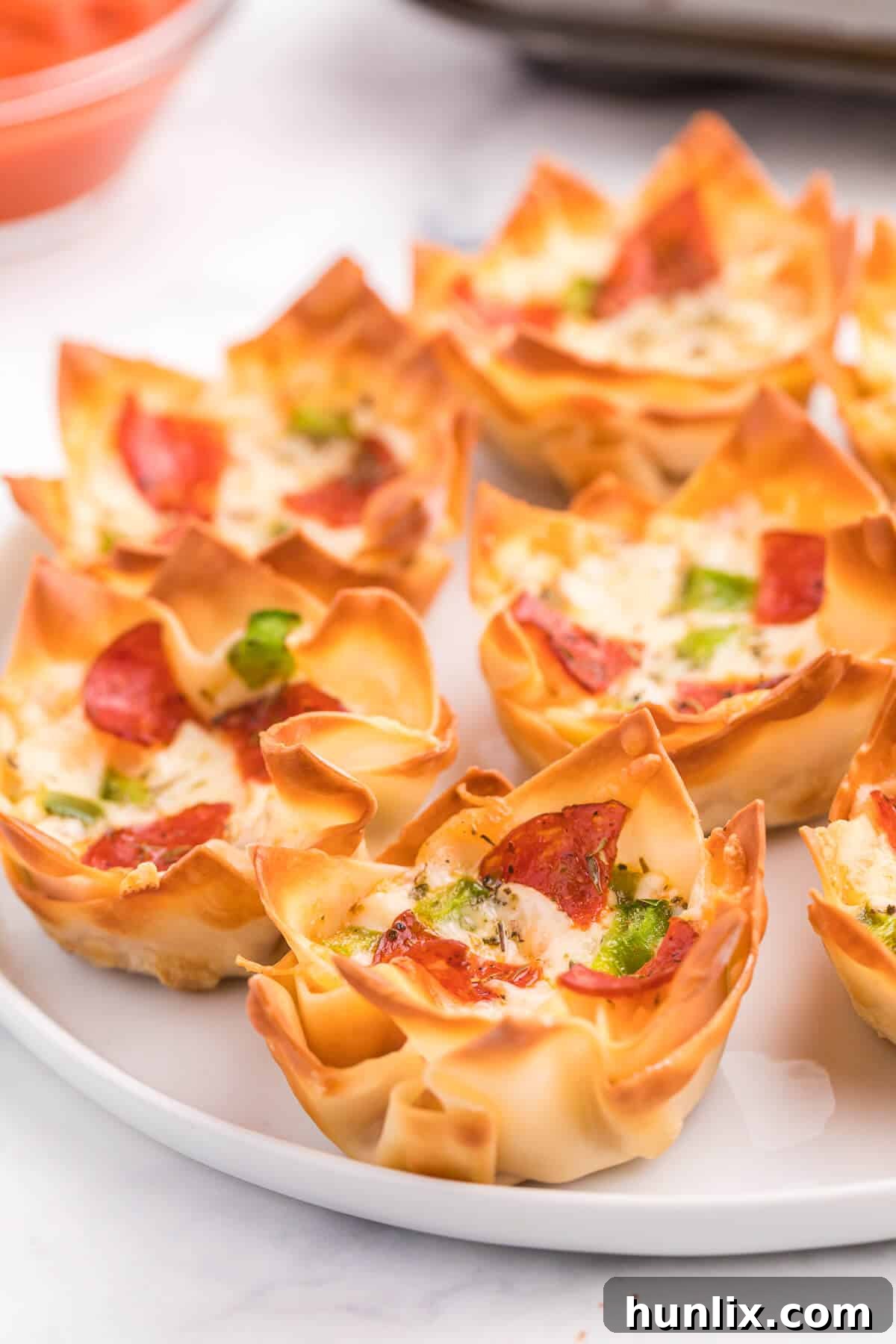 Pizza Wonton Cups Recipe - East meets West in this simple crunchy appetizer. A crispy wonton is filled with cheesy pizza goodness with any toppings you want!