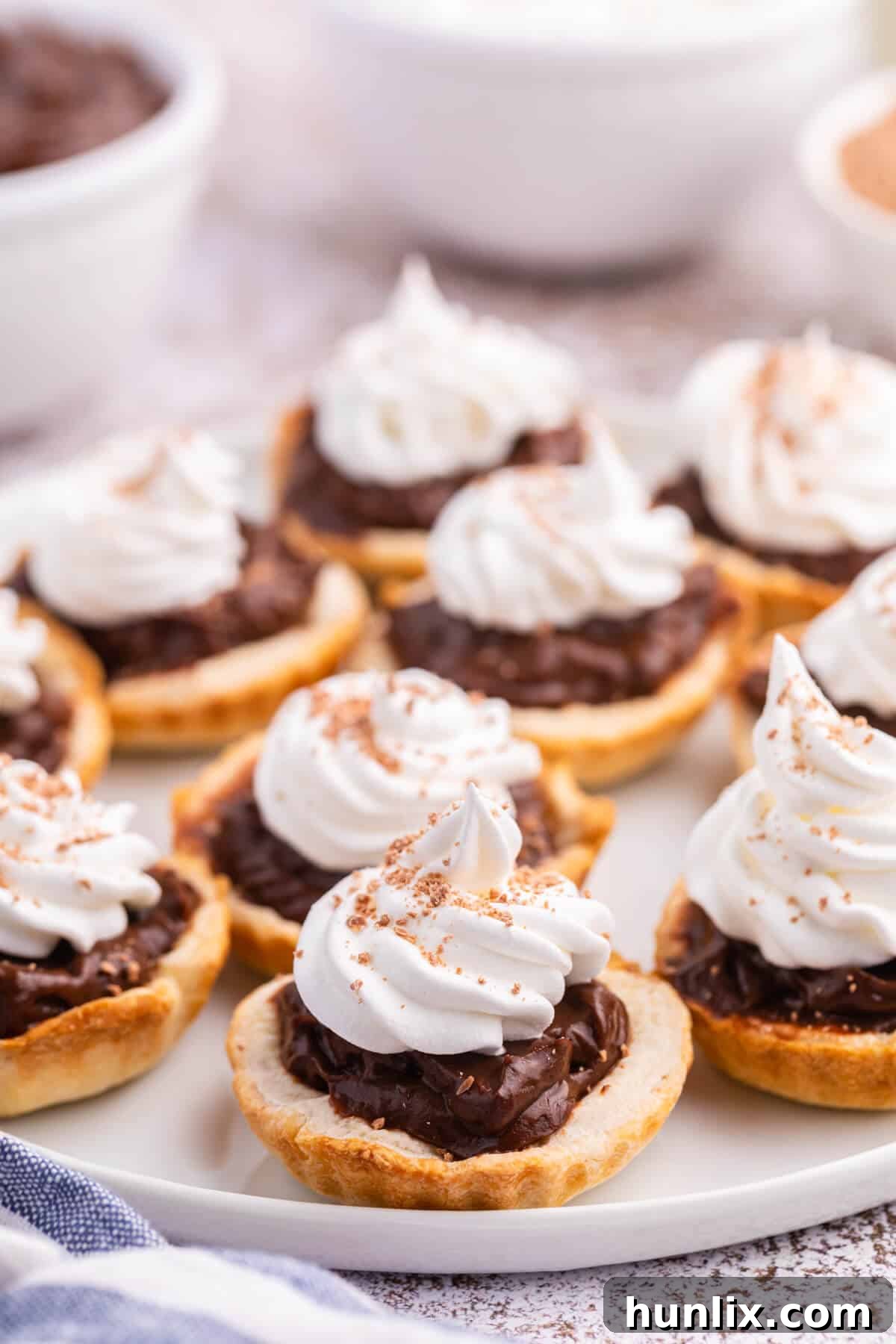 A charming plate of finished chocolate cream tarts, ready to be enjoyed.