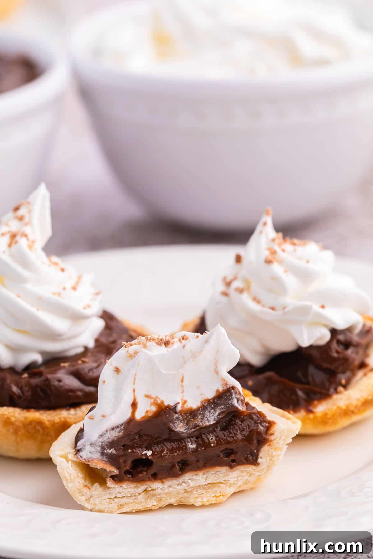 A sliced chocolate cream tart revealing its layers of crust, pudding, and whipped cream.