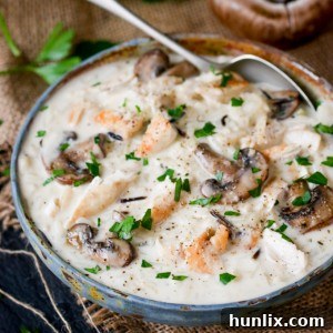 A deliciously rich bowl of Creamy Chicken, Wild Rice & Mushroom Soup, garnished with fresh parsley.