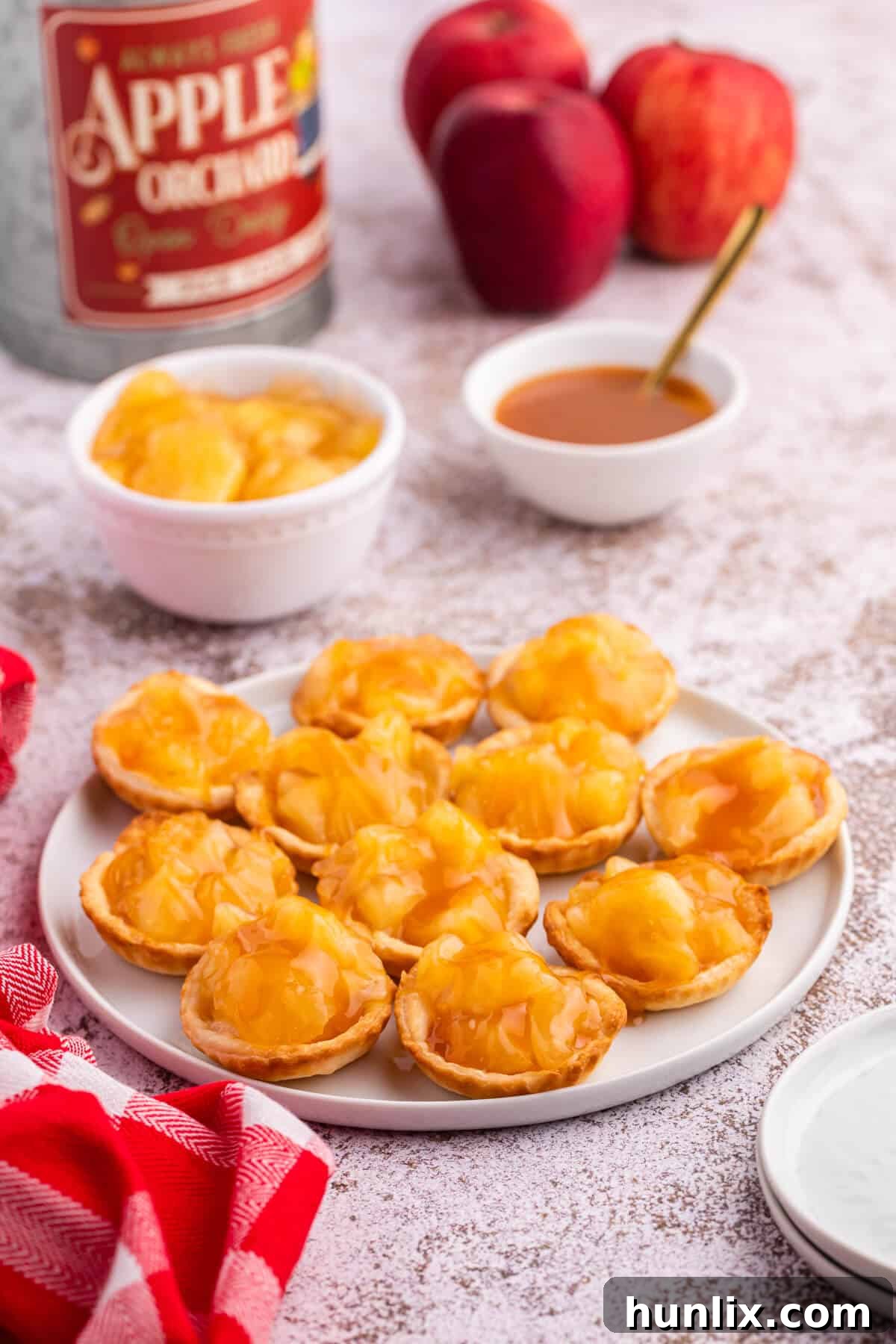 Close-up of baked caramel apple tarts on a white plate, showing the golden crust.